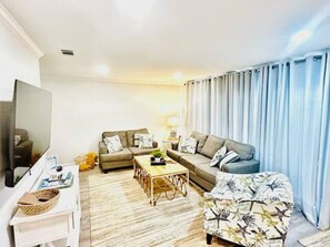 A living room with a sofa, armchair, coffee table, and a flat-screen TV.