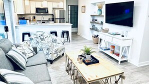 Un soggiorno moderno con un divano, un tavolino da caffè e una TV fissata alla parete.