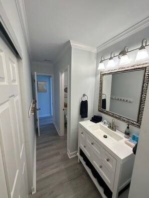 A bathroom with a white vanity, a large mirror, and a lighted vanity area.