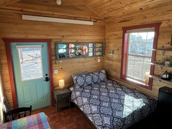 Cozy cabin with a bed, bedside table, and window offering a view of the outside.