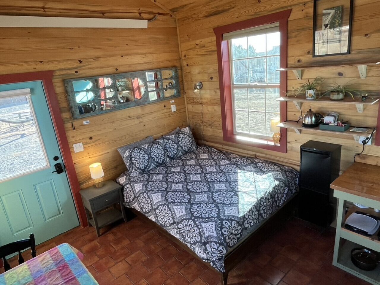 Une chambre confortable dans un chalet, avec un lit, une petite table, un bureau, un miroir et une fenêtre.