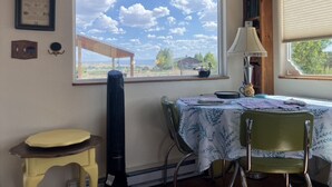 Een eethoek met een tafel gedekt voor twee personen, een raam met uitzicht op het landschap, en een radiator aan de muur.
