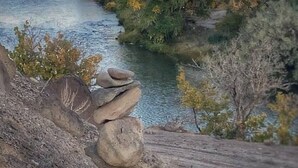 Een rivier die door een bergachtig landschap stroomt, met bomen en rotsen.