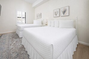 A bedroom with two beds, a window, and a rug.