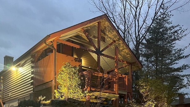 Un edificio moderno con fachada de madera, ventanas amplias y base de piedra.