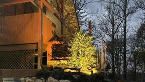 Un edificio moderno con techo inclinado y un área ajardinada con rocas y un árbol.