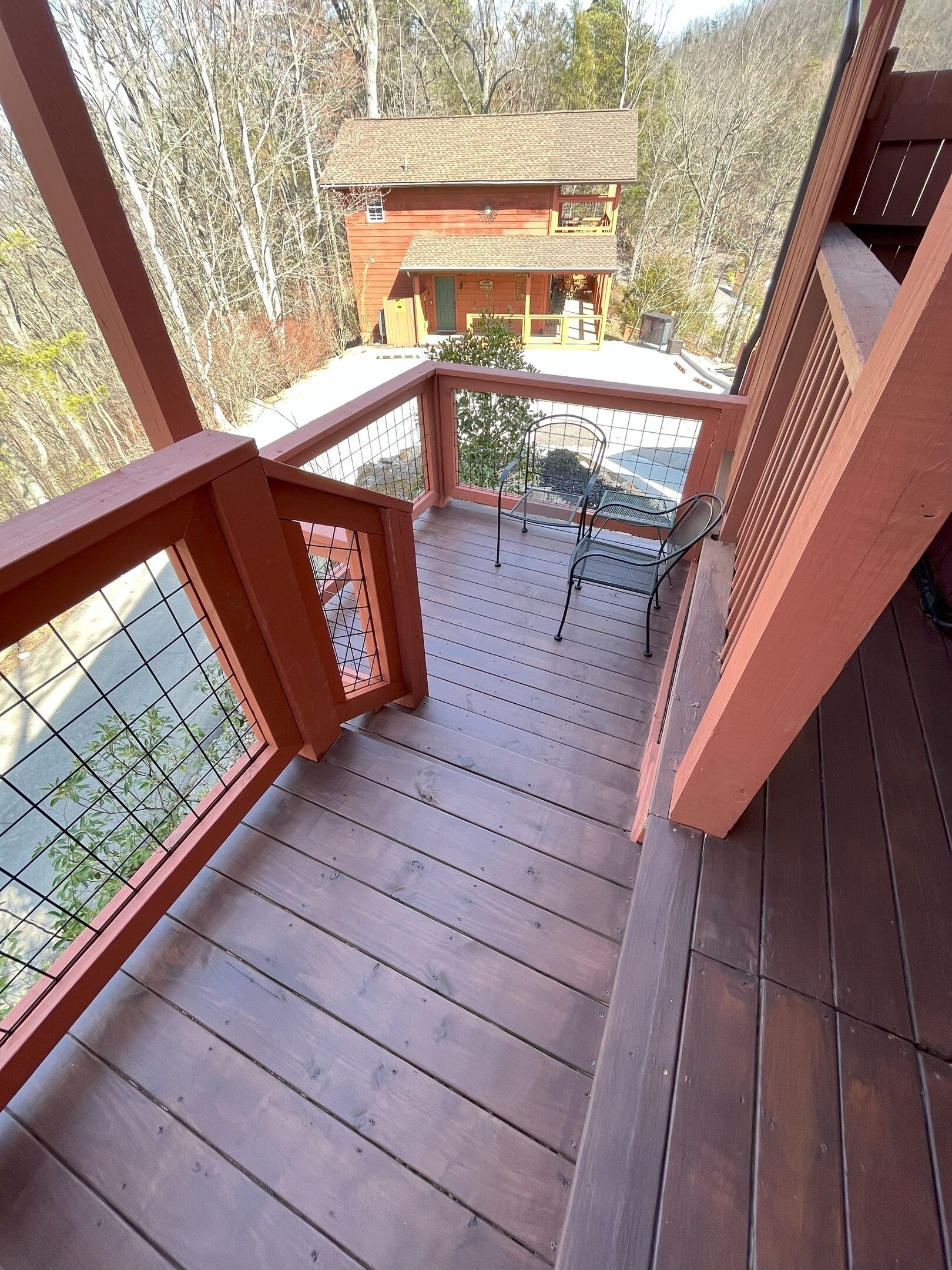 A wooden deck with a metal railing, a chair, and a view of a building in the background.