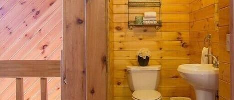 A wooden-paneled bathroom with a toilet, bidet, and shelf with toiletries.