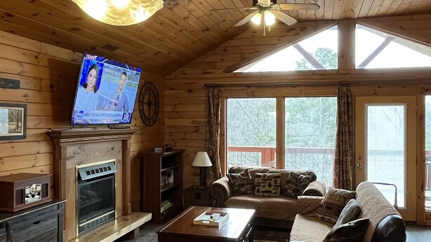 L’intérieur d’un chalet accueillant, avec une cheminée, des murs en bois, un téléviseur et un canapé.