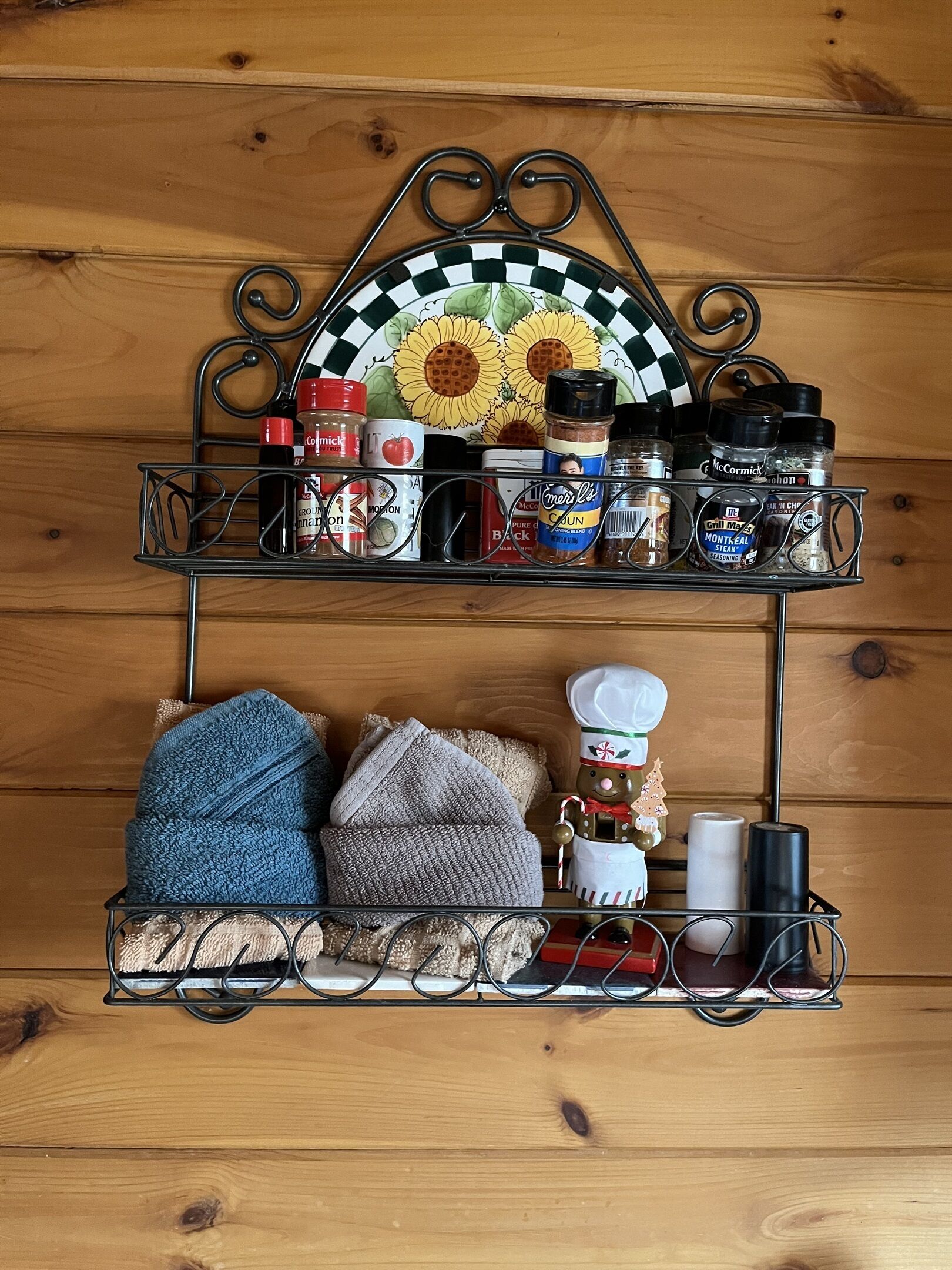 Una repisa de cocina con diversos condimentos, un plato decorativo y toallas de cocina.