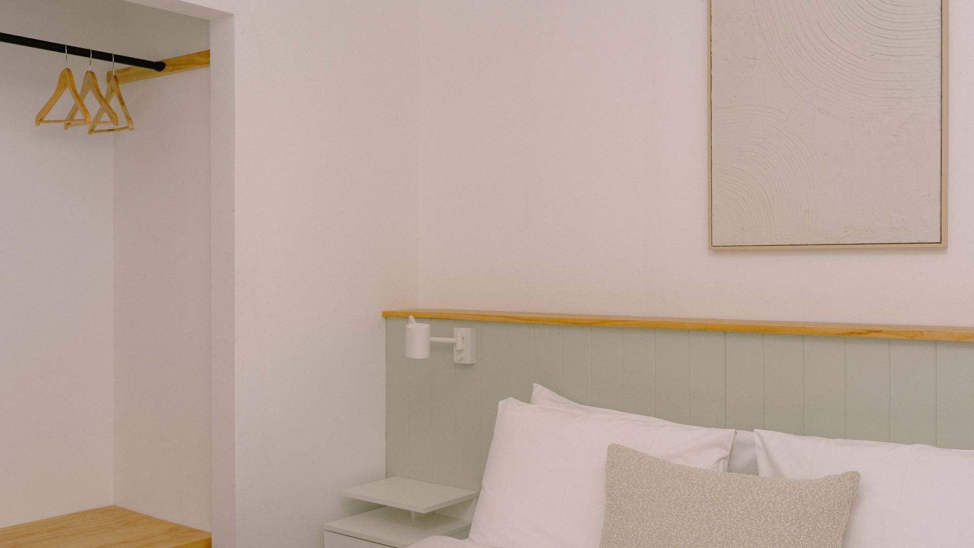 A bedroom with a bed, bedside table, and a wall-mounted light fixture.