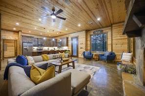 A log cabin interior with a living room, kitchen, and dining area.