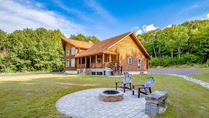 A log cabin with a deck, a fire pit, and outdoor seating.