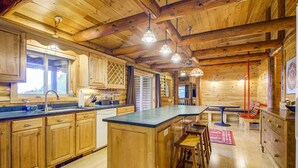 A wooden cabin interior with a kitchen, dining area, and bar.