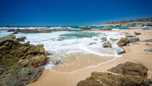 Une plage rocheuse où les vagues déferlent sur le rivage.