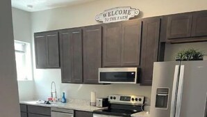 A modern kitchen with dark cabinets, stainless steel appliances, and a marble floor.