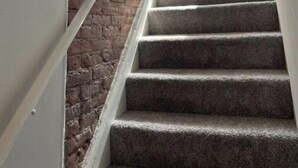A staircase with carpeted steps, a brick wall on one side, and a white railing. - Soulard|Completely new home|Walkability (St. Louis)
