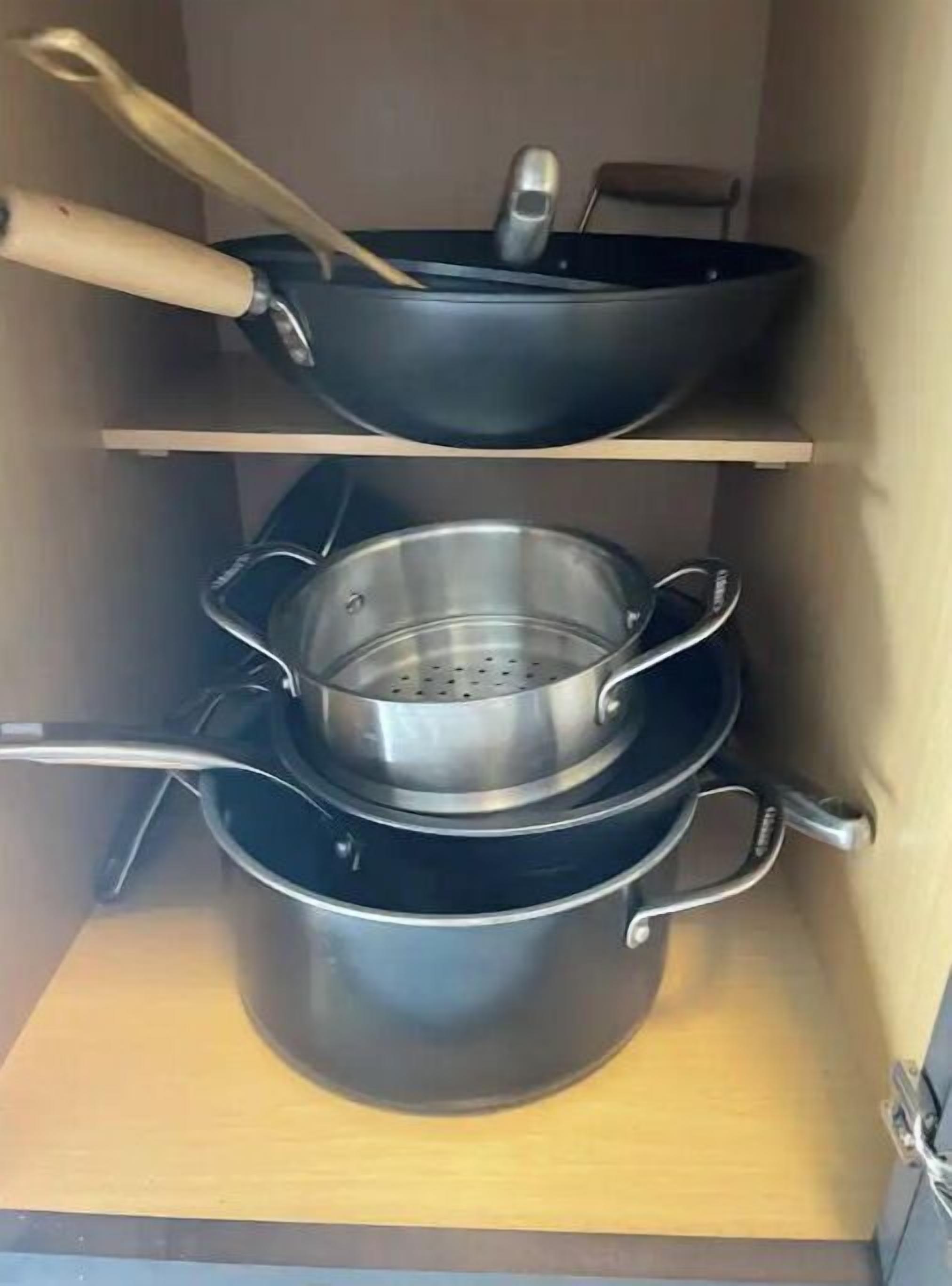 Eine Küche mit zwei schwarzen Töpfen auf Regalen, einer davon mit einem Sieb darauf.