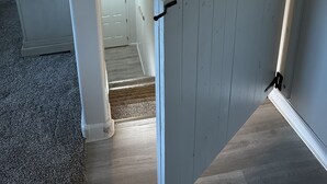 A staircase with a handrail, carpeted floor, and a door at the top.