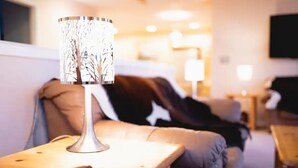 A cozy living room with a modern lamp on a wooden side table, a leather sofa, and a flat-screen TV mounted on the wall. - Amazing  Views--Spacious 3BR, outdoor barrel sauna, dog friendly (Hartsel)