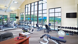 Ein Fitnessstudio mit unterschiedlichen Trainingsgeräten, großen Fenstern und Blick ins Freie.