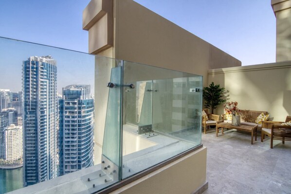 Ein Balkon mit Glasgeländer mit Blick auf eine Skyline und hohe Gebäude.