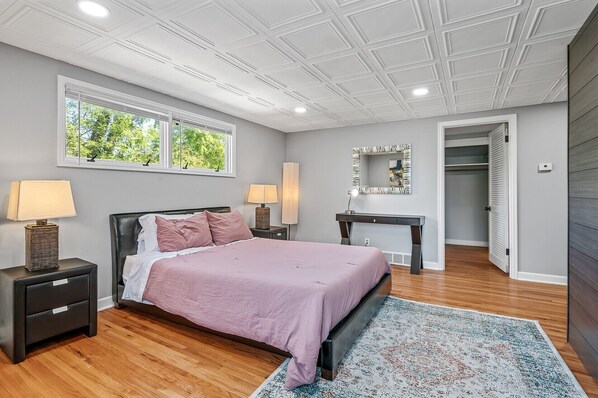 Un dormitorio con cama, mesitas de noche, escritorio, espejo y vestidor.