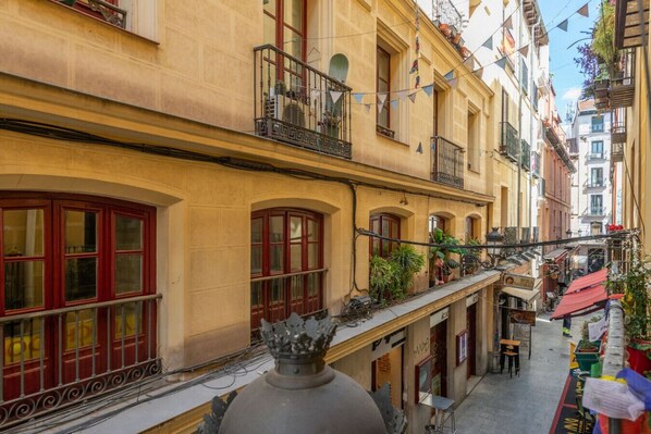 A narrow street with buildings featuring balconies and arched windows.