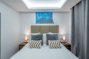 Une chambre à coucher comprenant un lit, deux tables de chevet, une tête de lit, un puits de lumière et un tableau accroché au mur.