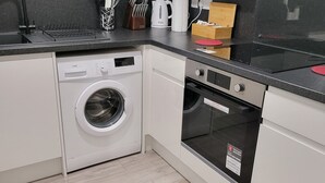 Eine kleine Küche mit Waschmaschine, Backofen und Kaffeemaschine.