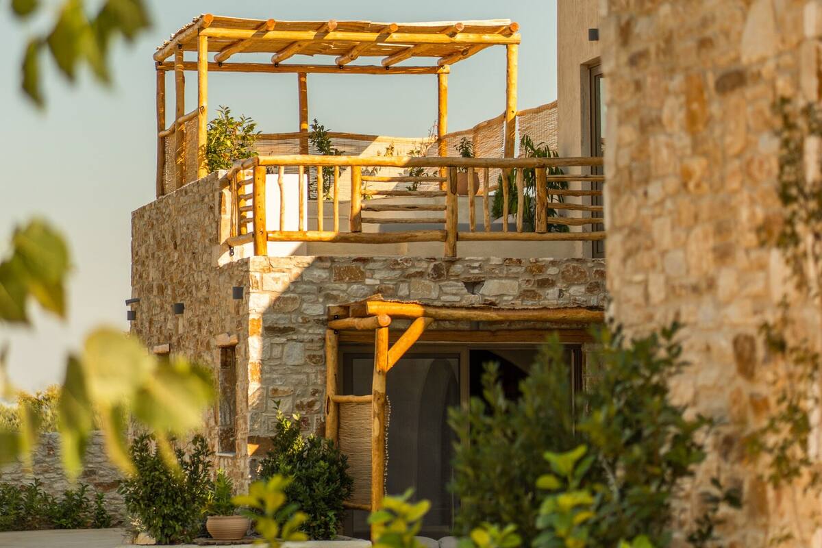 A stone building with a wooden balcony and a pool.