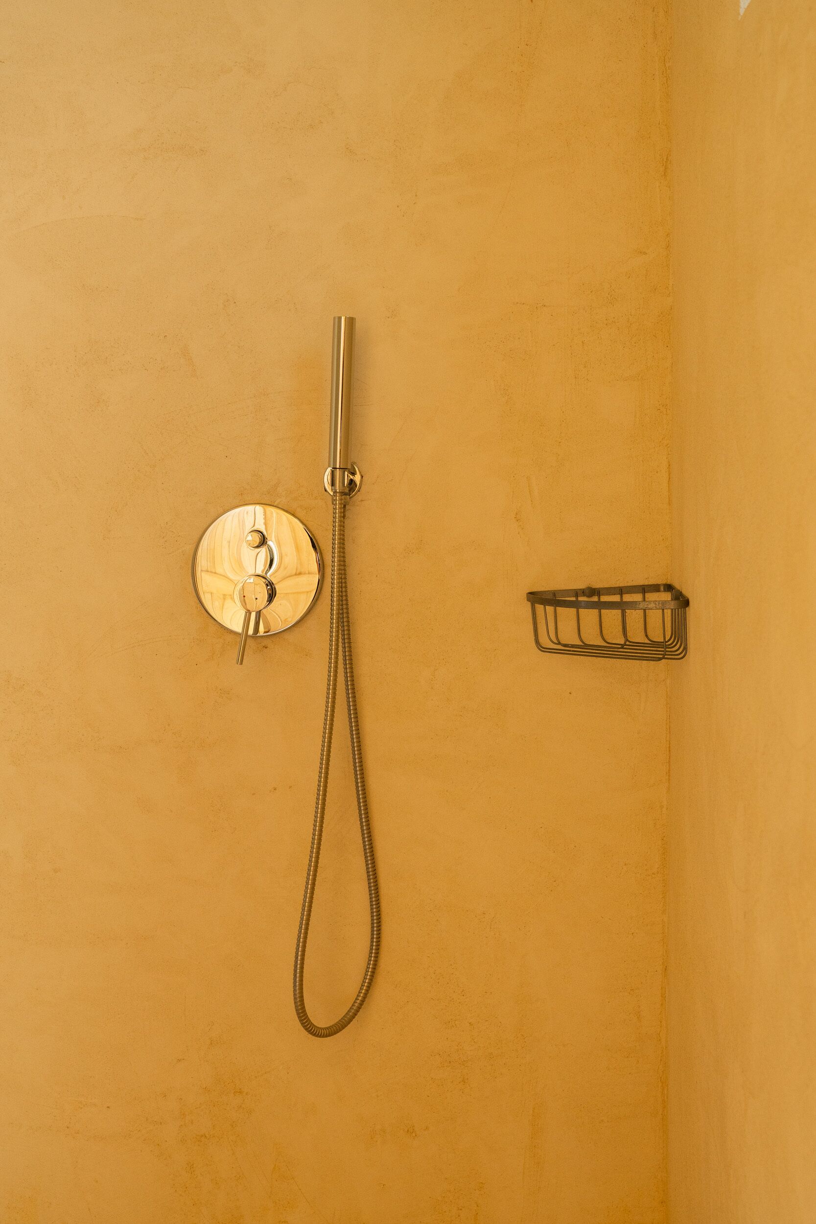 A shower with a handheld showerhead and a wall-mounted control panel.