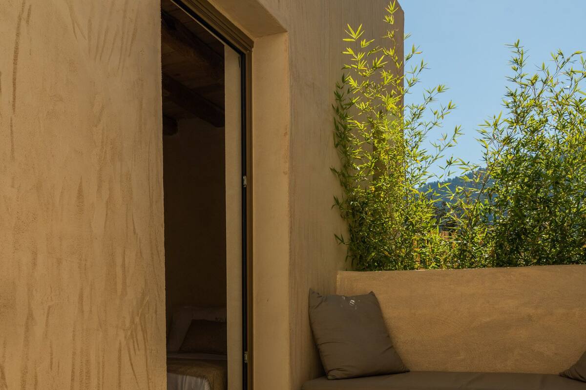 A cozy outdoor seating area with a sofa, a wooden stool, and a bowl of fruit.