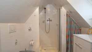Une petite salle de bain compacte, équipée d’une douche, de toilettes et d’un lavabo.