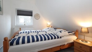 Un lit simple avec une couvre-lit à rayures, une lampe de chevet et une table de chevet avec une lampe.
