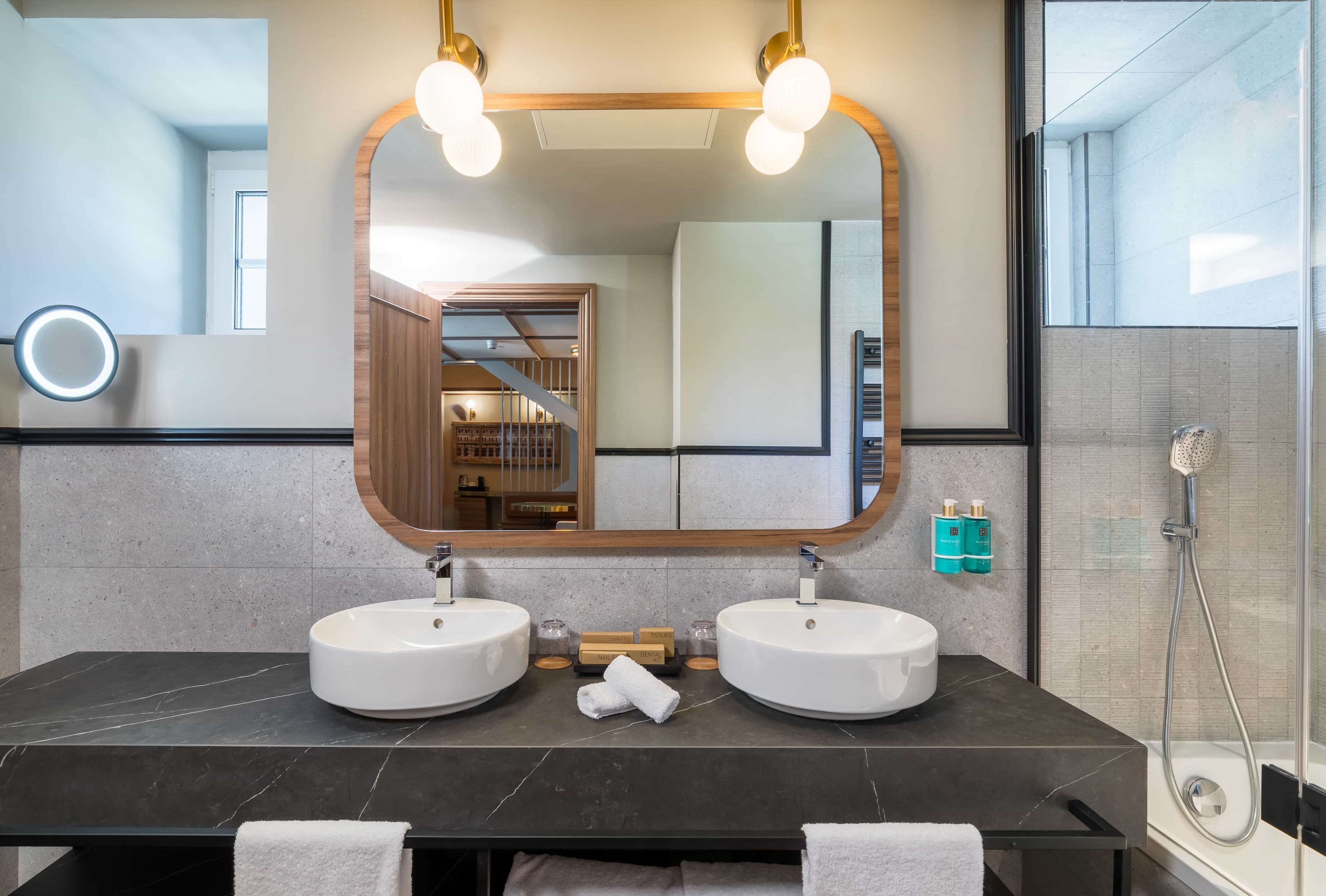 Un bagno moderno con due lavabi, uno specchio grande e una doccia.