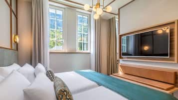 Une chambre d’hôtel avec un grand lit, un téléviseur fixé au mur et une fenêtre avec des rideaux.