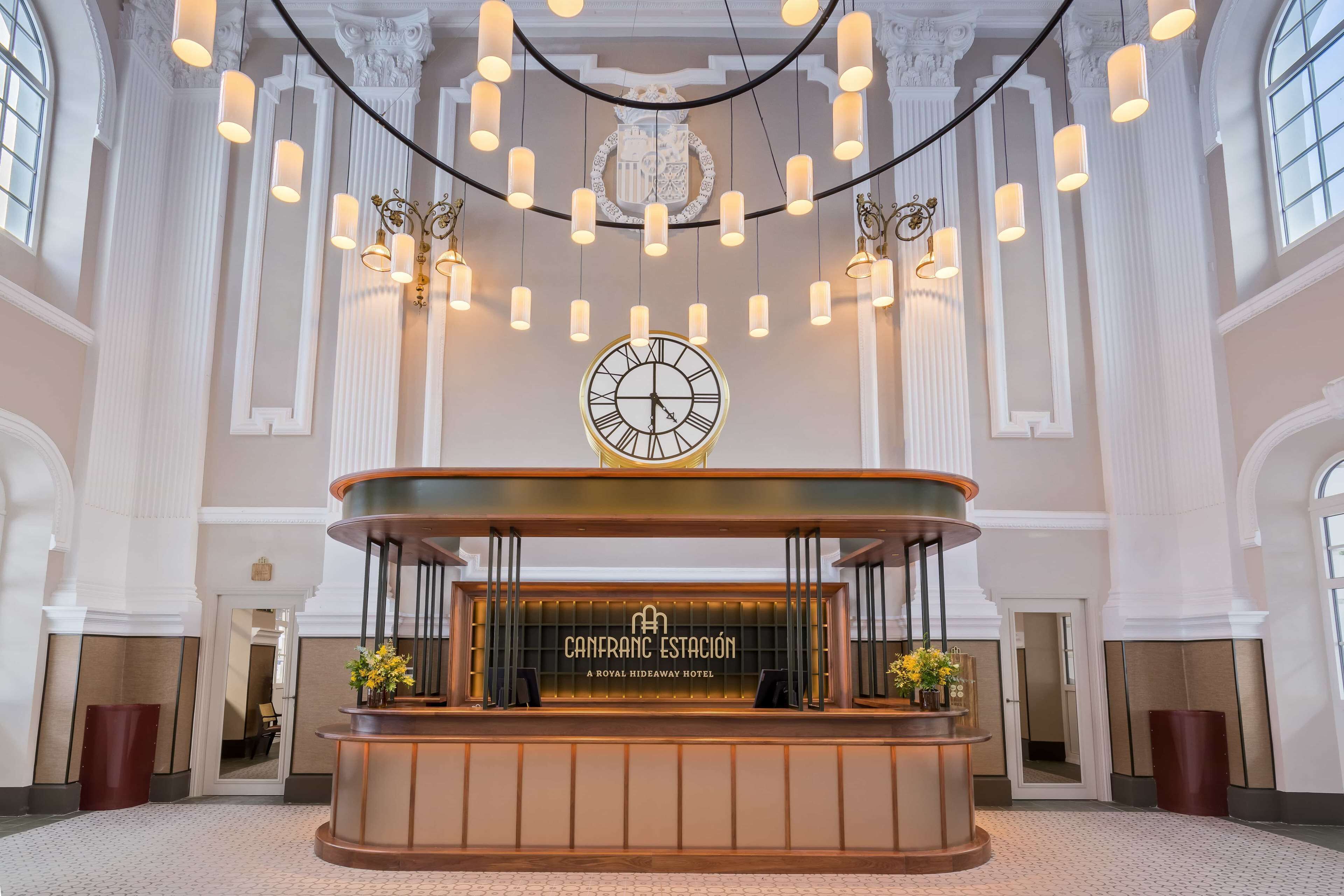 A reception area with a clock, a reception desk, and a chandelier.