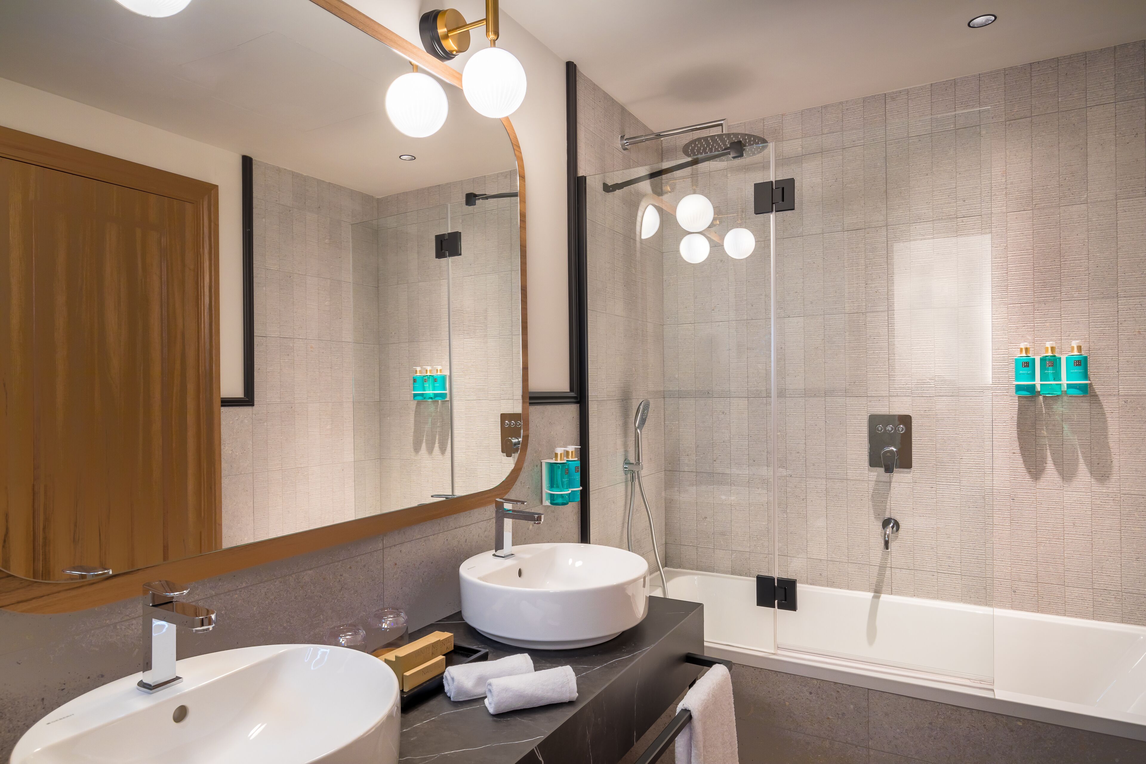A modern bathroom with a large sink, a bathtub, and a glass-enclosed shower.