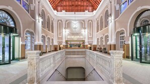A spacious lobby with a high ceiling, arched windows, and a central reception desk. - Canfranc Estación, A Royal Hideaway Hotel - Gran Lujo (Canfranc)