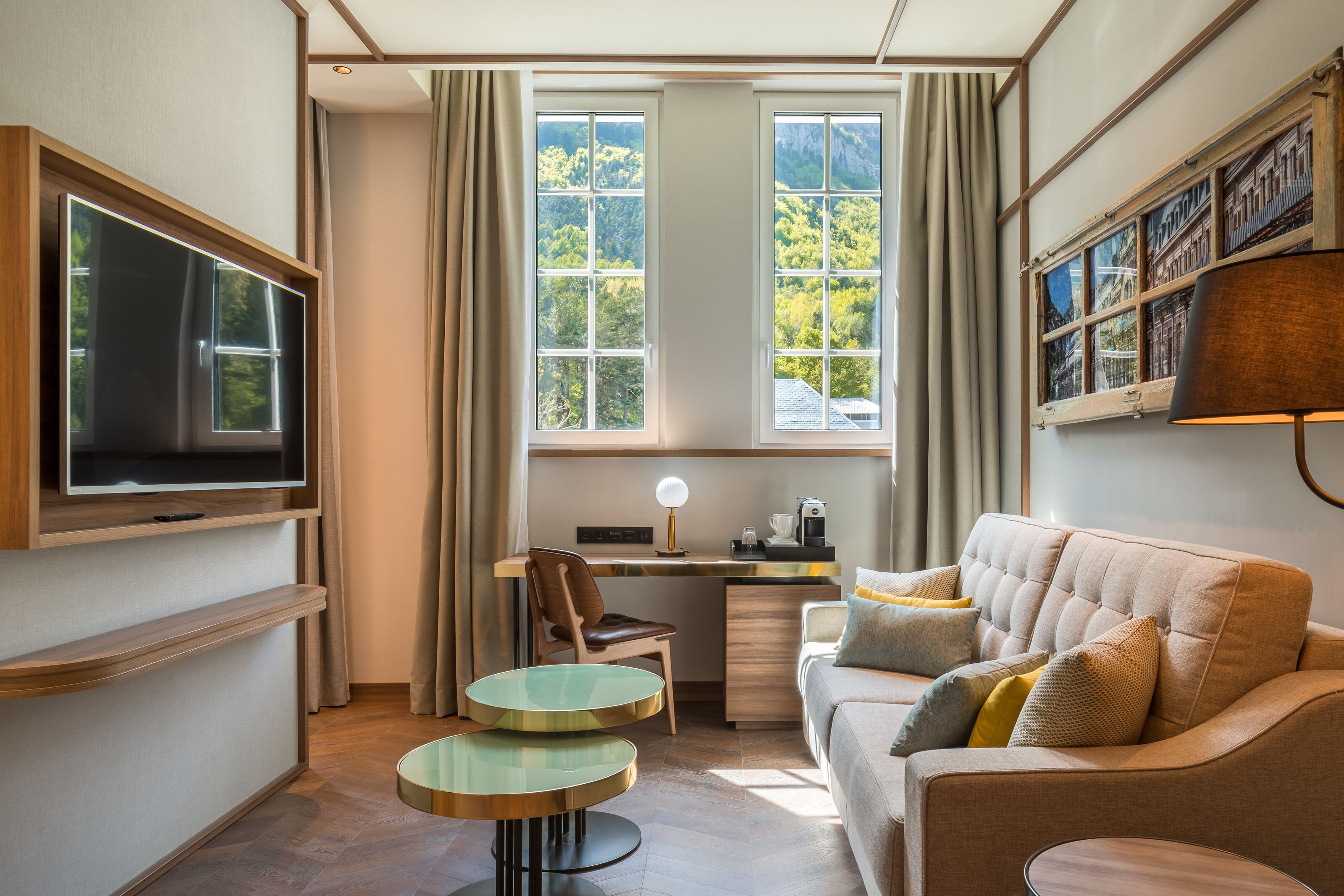 A modern room with a TV, a desk, a sofa, and a coffee machine.