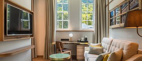 A modern room with a TV, a desk, a sofa, and a coffee machine.