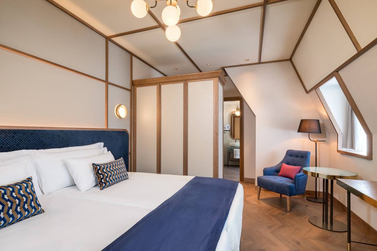 A bedroom with a bed, a chair, a table, and a ceiling light.
