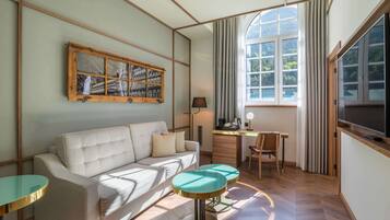 A modern living room with a sofa, a small table, a TV, and a window with curtains.