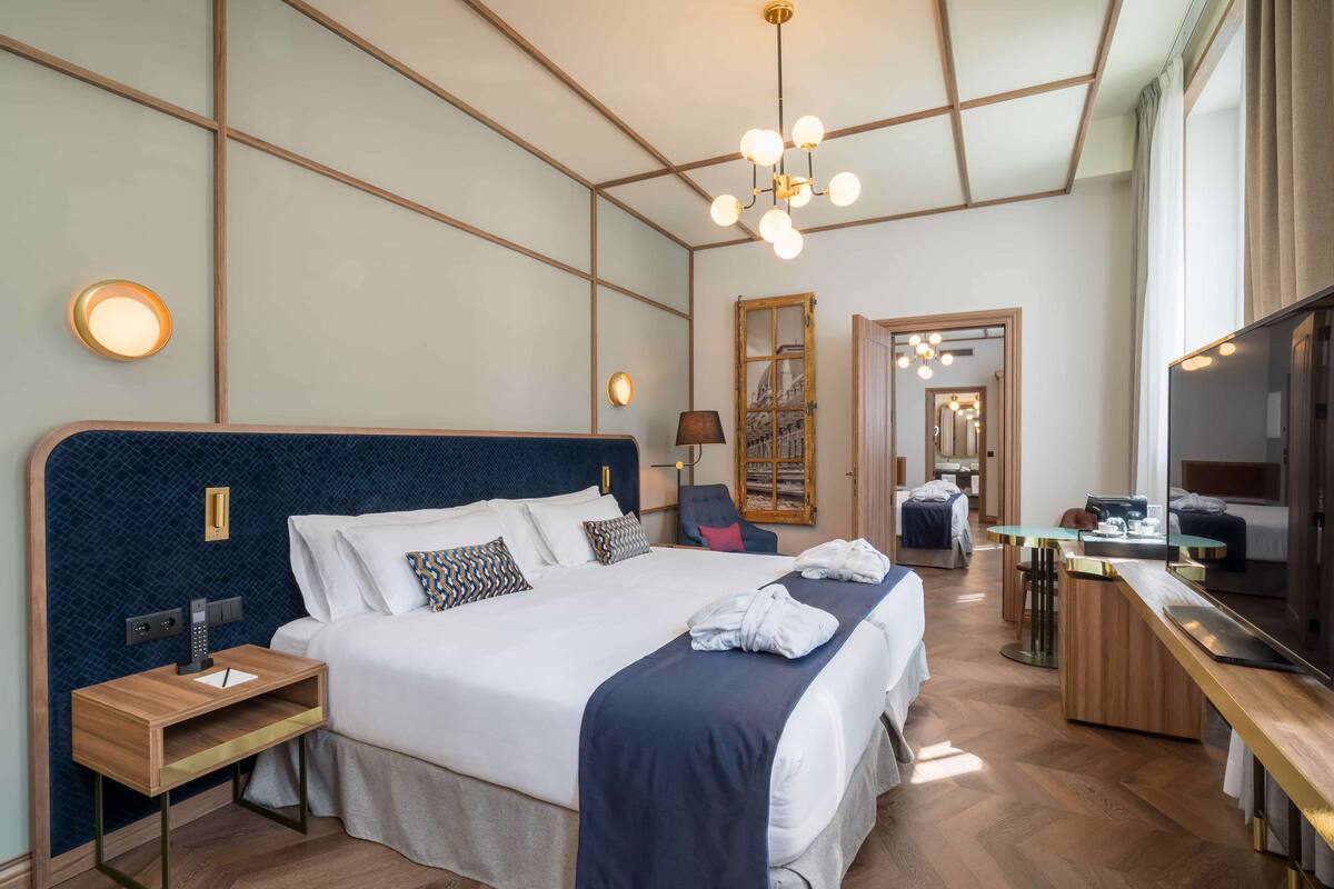 A hotel room with a large bed, bedside tables, a desk, and a mirror.