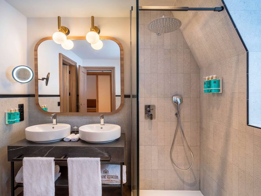 Une salle de bain moderne avec deux lavabos, un grand miroir et un espace douche.