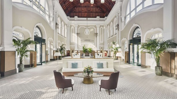 A spacious lobby with a high ceiling, large windows, and a central seating area with a round table. - Canfranc Estación, A Royal Hideaway Hotel - Gran Lujo (Canfranc)