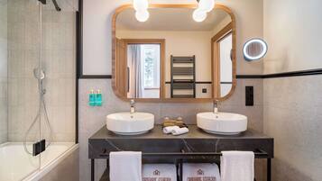 A modern bathroom with two sinks, a large mirror, and a shower.