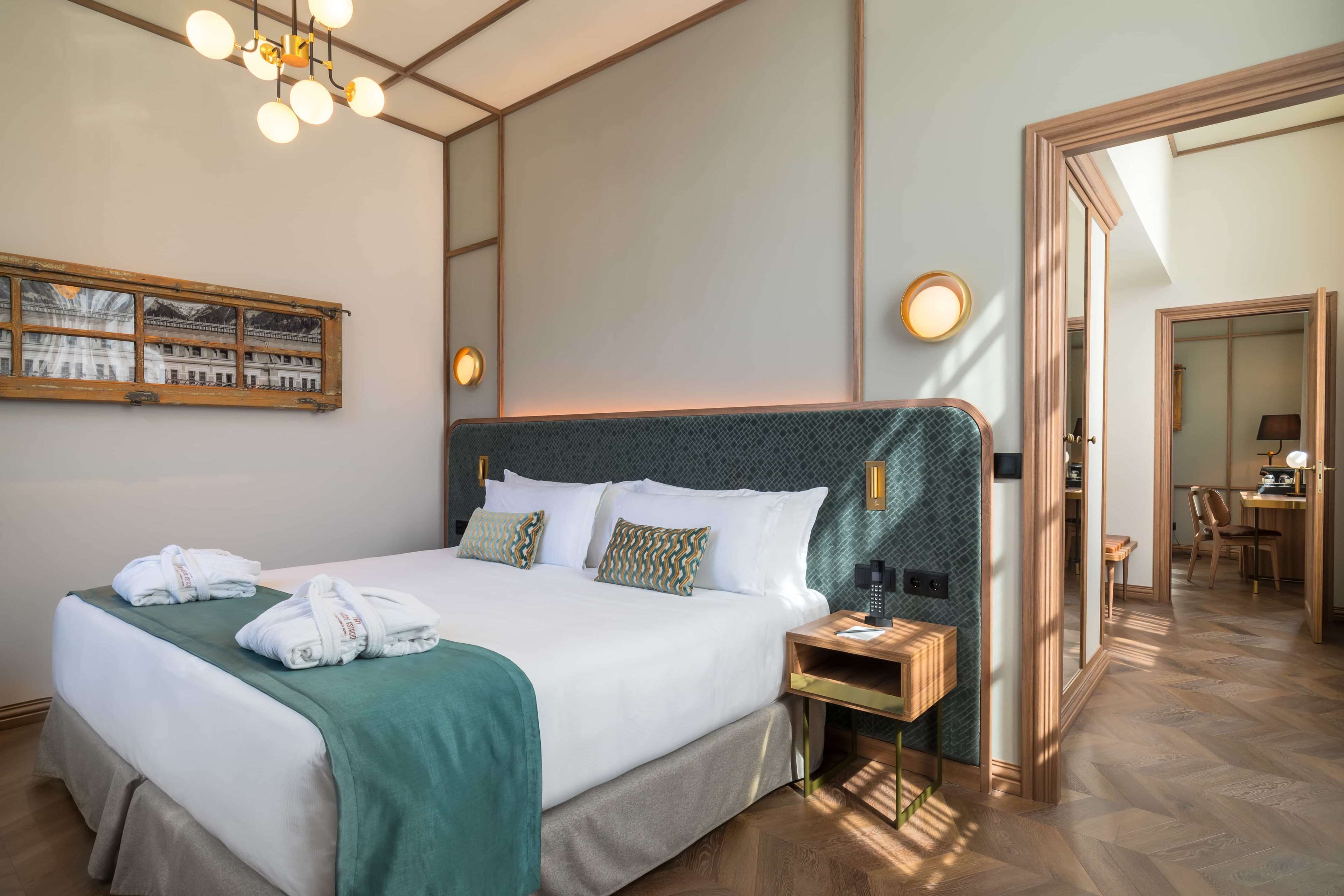 A hotel room with a large bed, a bedside table, a mirror, and a view of the hallway.