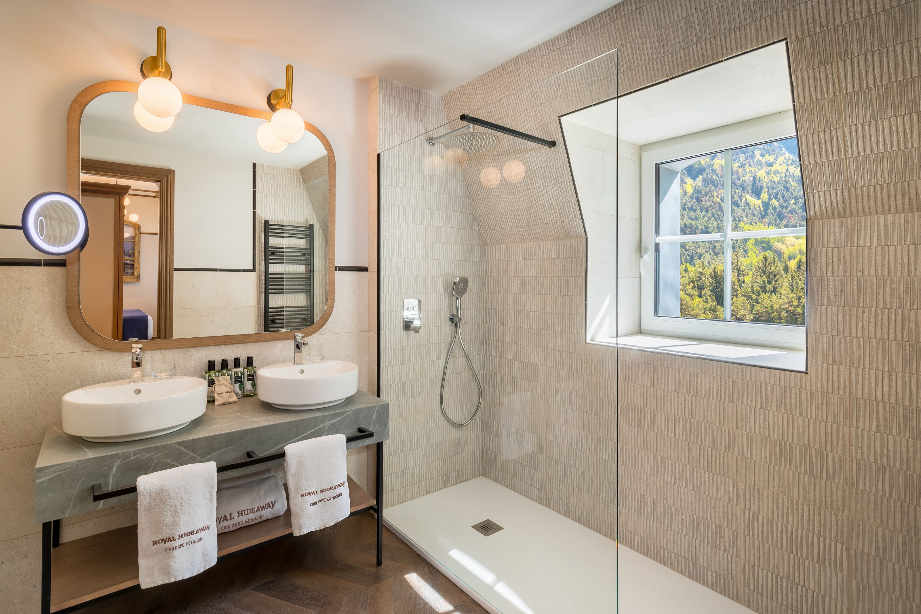 Une salle de bain moderne avec deux lavabos, un grand miroir et une douche.
